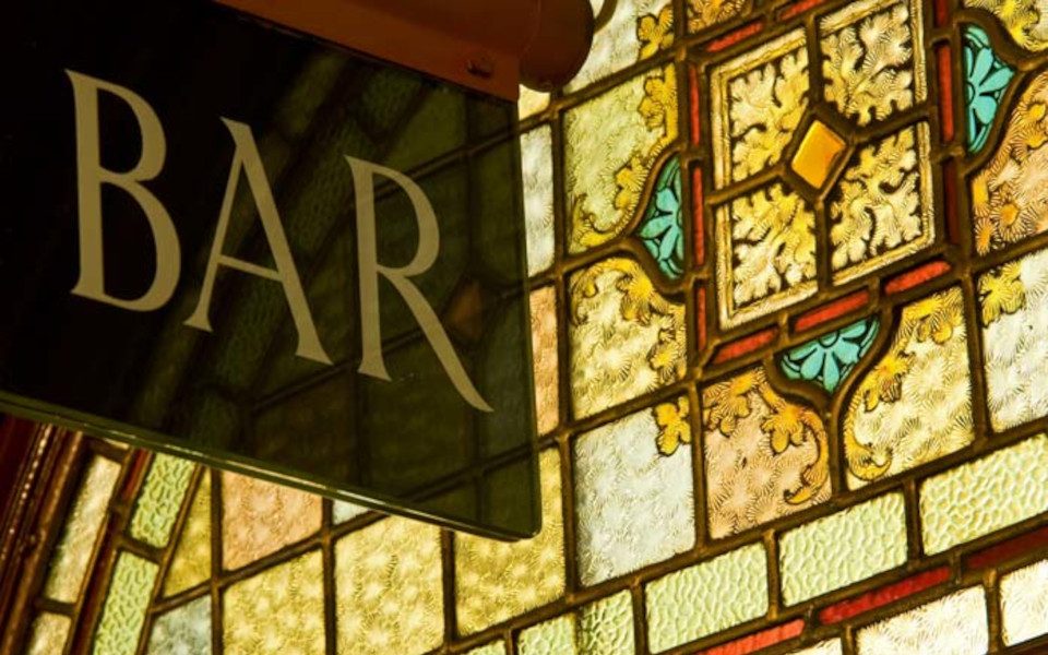 A sign reading BAR with stained glass windows behind