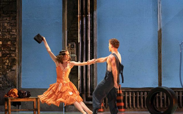 Abigail Prudames as Myrtle and Matthew Topliss as George in The Great Gatsby. Image by Emma Kauldhar Resized Abigail Prudames in an organge dress holding a bag in the air and holding onto dancer Matthew Topliss as she leans back