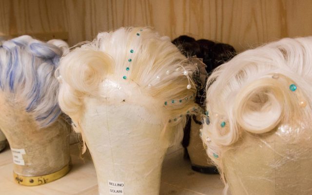 Three wigs on wig stands - two are white with blue jewels and white pearls, and one is white with blue streaks through it