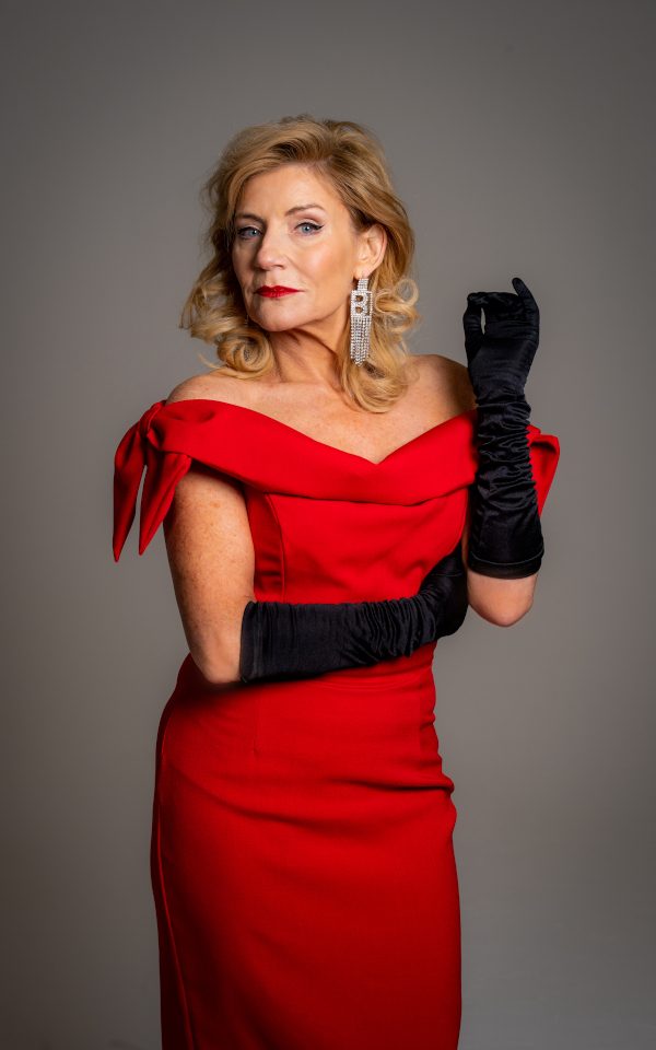 Michelle Collins in a red dress with long black gloves
