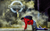 Connor Curren (Christopher) in The Curious Incident of the Dog in the Night-Time A boy in a red hoodie carrying a backpack is on his hands and knees upstage in front of a digital Paddington Tube Station sign
