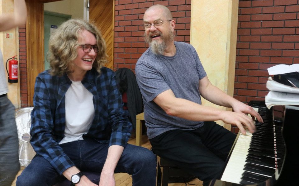 Gabriel and Pete Rosser sit together by a piano