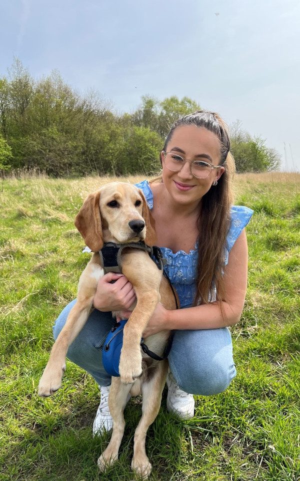 Jessica Davison knelt down holding up her puppy in a field