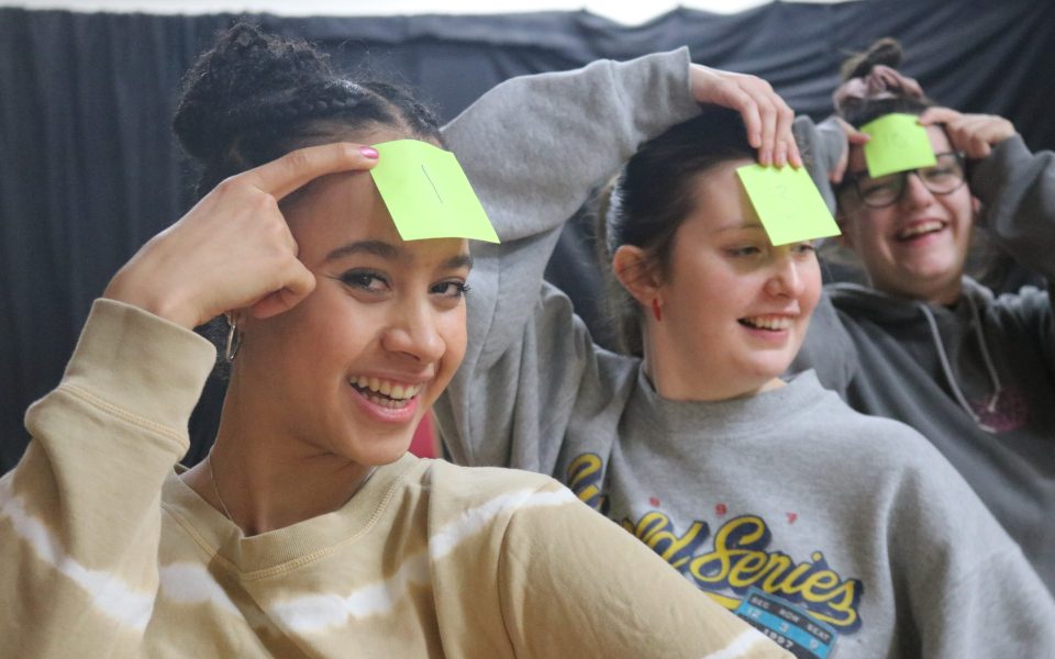 Three actors smiling with post-it notes stuck to their foreheads