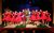 Seymour and Ronnettes, LSOH. Credit Kerry Maule The cast of Little Shop of Horrors of stage. Gabriel is Seymour holding a plant next to a line of girls in red dresses