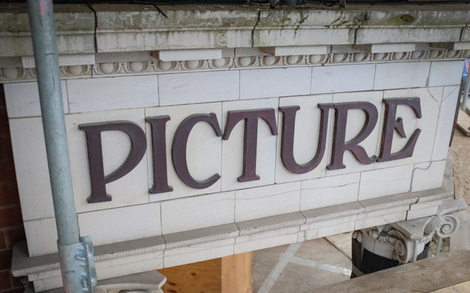 CLose up of facade tiles reading 'picture' with scaffolding