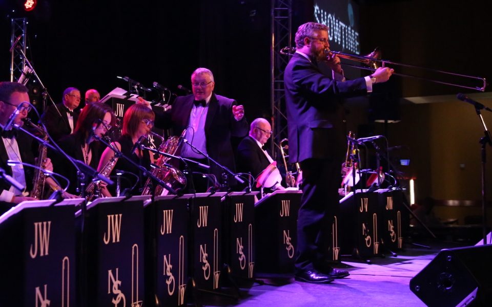 Northern Swing Orchestra on stage with conductor and lead trombone player stood at the front