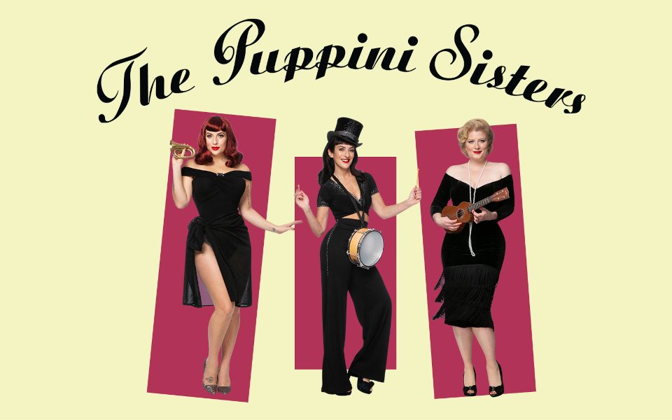 The Puppini Sisters all wearing black vintage-style outfits and playing small instruments, a trumpet, drum and ukulele