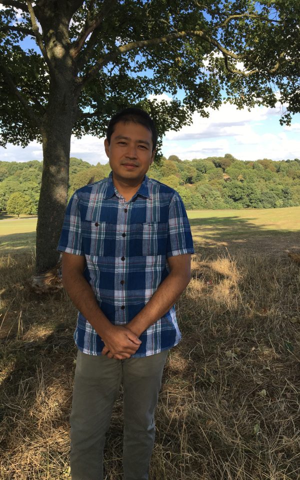 Hu Chen standing in a field in front of a tree