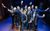 Sean Jones (Mickey) & The Cast of Blood Brothers- Blood Brothers UK 2022 Tour- Photo by Jack Merriman A group of people in suits holding up bits of paper