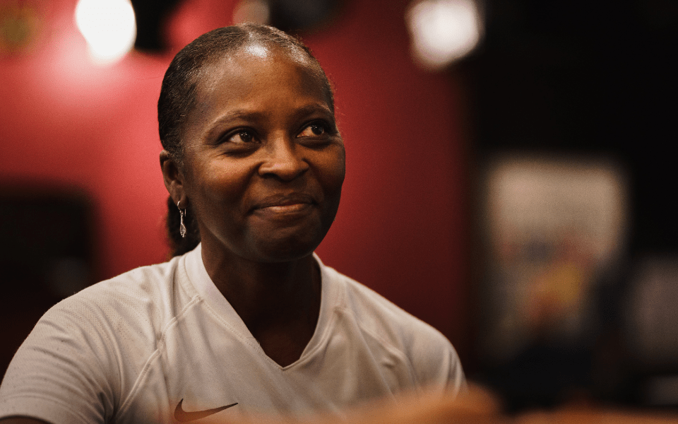 A picture of a woman from the shoulders up. She is smiling and looking up.