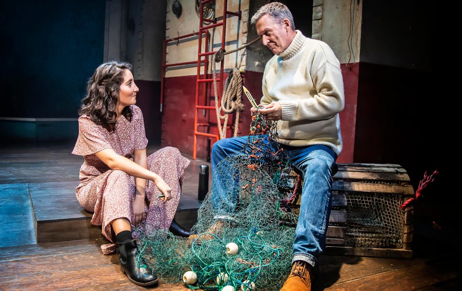 A man holding a fishing net talking to a woman sitting down