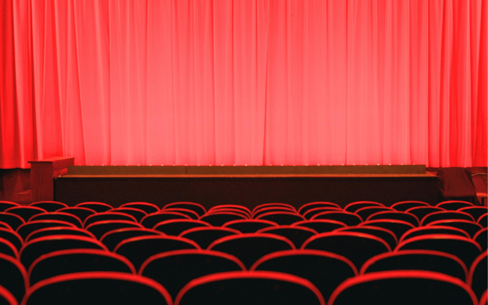Rows of red cinema chairs in front of red curtains