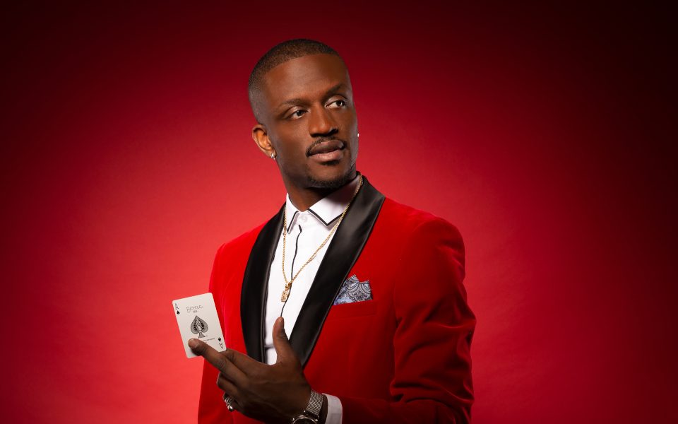 Magical Bones holding an ace card wearing a red tuxedo jacket