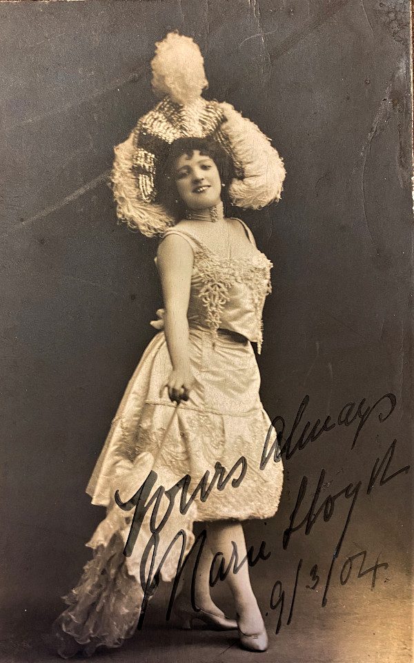 Marie Lloyd Signed photograph. She is wearing a feathered hat and rouched dress, smiling. The signature reads: Yours always, Marie Lloyd 9/3/04