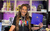 Jessica Davison A woman in front of a merchandise stall holding up a SIX programme