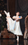 Rachael Gillespie as Clara A ballerina in a long light pink dress with her leg in the air, holding a nutcracker