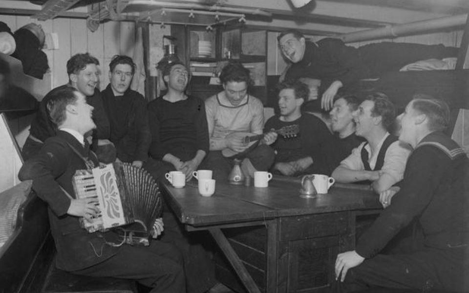 Safely at anchor some of the crew enjoying a sing-song on the mess deck.