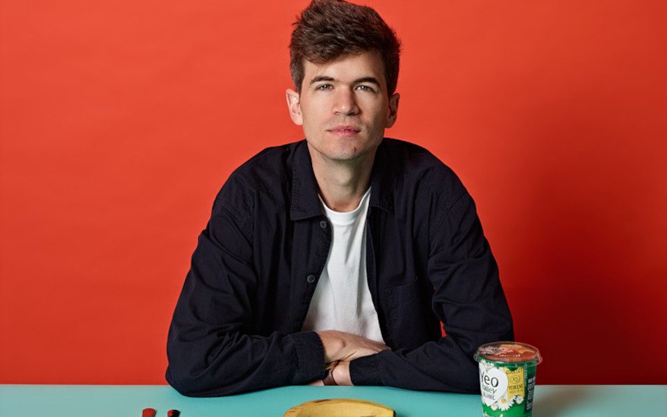 Ivo Graham sitting at a table with yogurt, a banana and cutlery.