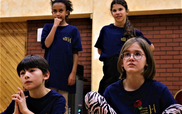 4 young members look on inquisitively. A boy and a girl sat in front of two girls stood behind.