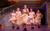 Pride and Prejudice* (*sort of) (3) Five woman standing in a 'V' formation wearing white dresses and rubber gloves. They swish their skirts while the woman at the front sings into a microphone.