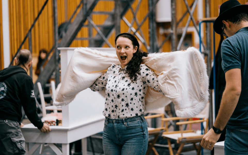 Jennifer France singing and holding up a sheet behind her