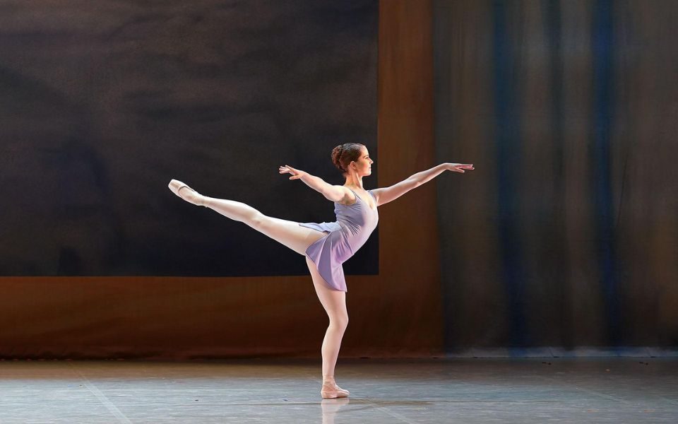 Dominique Larose in a ballet pose, standing on one leg with her arms out