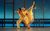 Dominique Larose A man and woman have their arms around each others' shoulders and lean forward in a ballet pose. The woman has her leg straight up in the air as she stands on pointe.