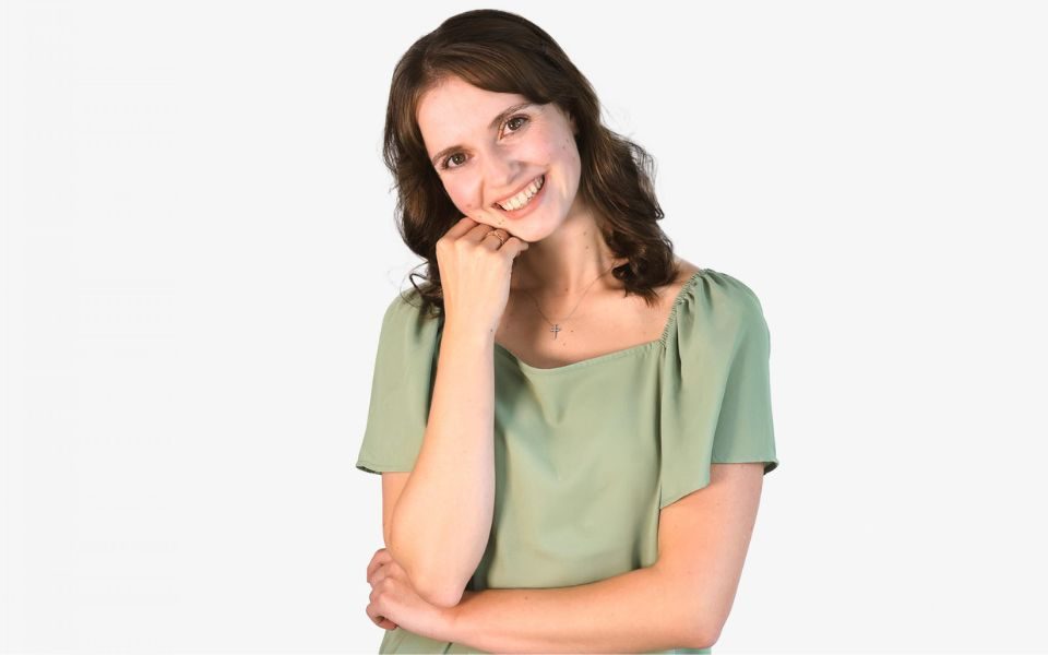 A headshot of Dominique Larose. She wears a green top and leans her head on her hand