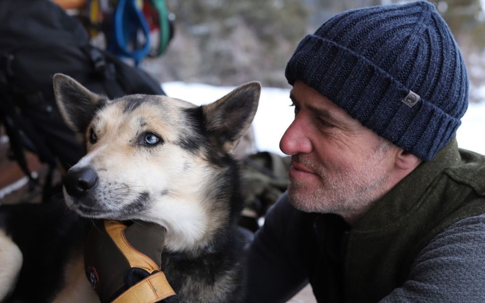 Gordon Buchanan in a black winter hat with his face next to a dog