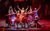 LAOS West Side Story A production photo for LAOS West Side Story. Dancers in colourful dresses stand in formation with their arms out in a pose, smiling at the audience.