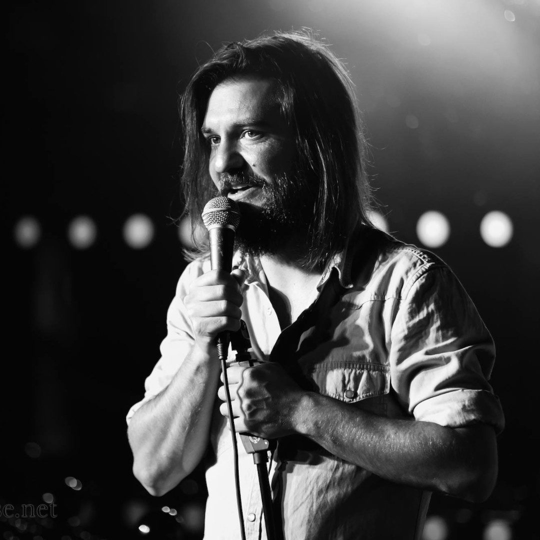 Matt Reed is on stage at at Manchester Bierkeller holding a microphone.