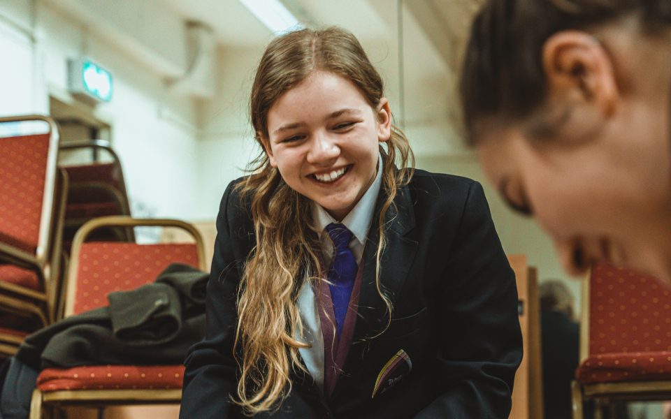 A student smiles, looking to her friend as they take part in a workshop. Credit: Kerry Maule