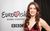 Lucie Jones Lucy Jones is wearing a velvet red dress. She is in front of a Eurovision Song Contest poster.