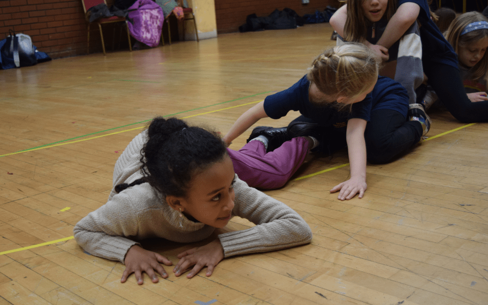 Primary school aged children making a dragon shape with their bodies.