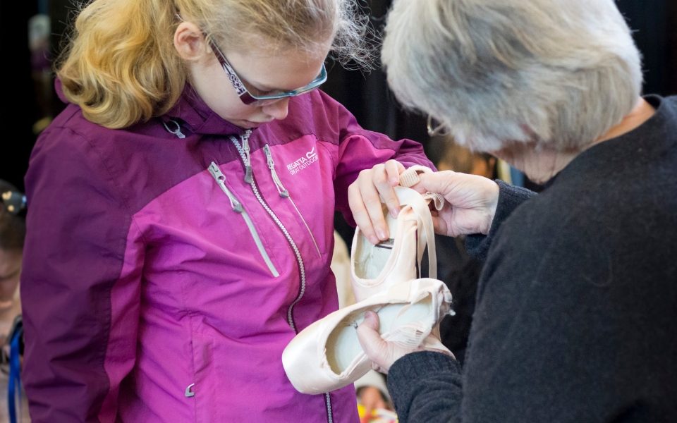 A woman touching ballet shoes on a touch tour