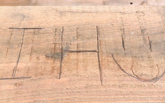 Wood with the letters IH carved into it alongside a smiley face