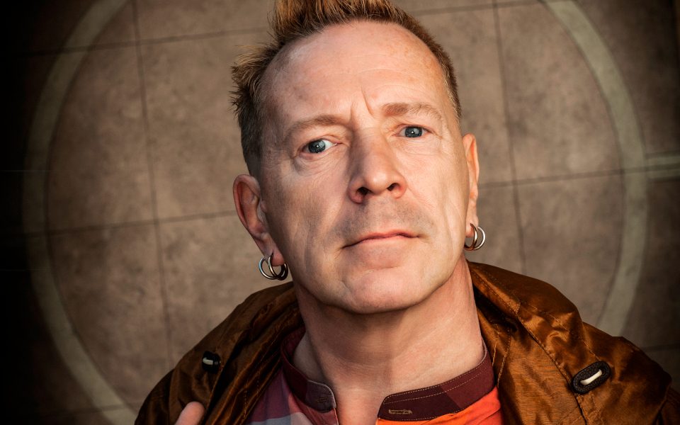 John Lydon stares into the camera against a beige backdrop.