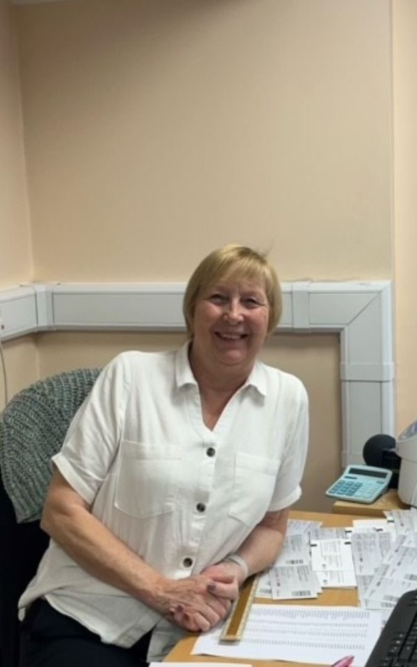 Sat at her desk, Judith smiles to the camera.