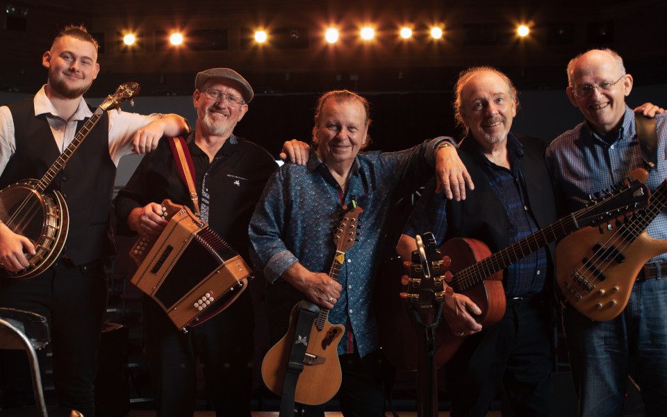 The Fureys take a group photo with their instruments. Instruments include accordion, guitars and a banjo.