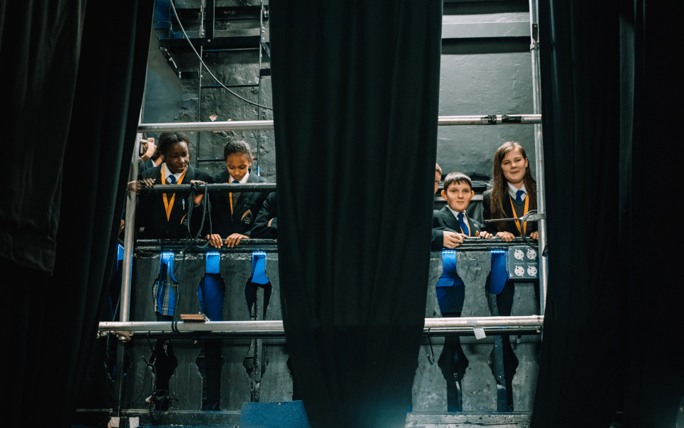 A group of secondary schoolchildren stand in the gallery bridge during a tour of City Varieties Music Hall
