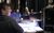Students receive a tech talk. Backstage, students huddle around a tech desk as Sean delivers a tech talk.