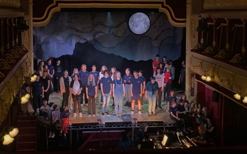The young people of LGYT stand on stage, with the Addams family - including Miri and Ellie - at the front. Credit: Kate Southam