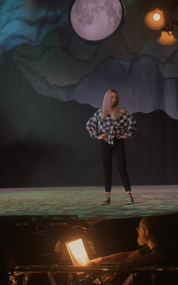 Miri stands on stage as Wednesday with her hands on her hips. Credit: Kate Southam
