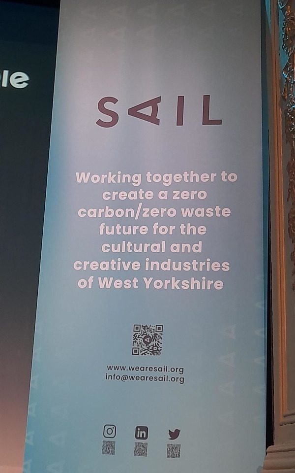 A blue banner at the SAIL event. The banner reads, 'Working together to create a zero carbo/zero waste future for the cultural and creative industries of West Yorkshire.'
