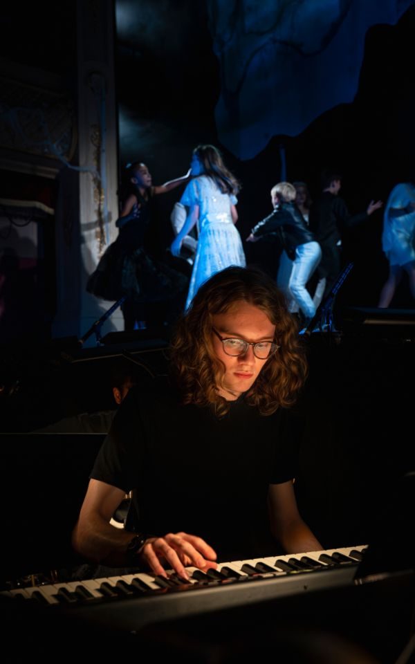 Gabe is sat at his keyboard during rehearsals, the stage of The Addams Family just behind him. Credit: Chris Coote