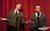 Hancock's Half Hour A man gestures enthusiastically to a man looking unimpressed. They hold scripts and stand in smart clothes behind microphones. They are in front of a red curtain backdrop.
