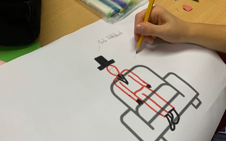 A young people draws a character, annotating it with facts about them, including their name and age