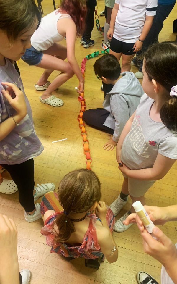 Young people piece together a paper chain, its links inscribed with what they enjoyed most over the week.