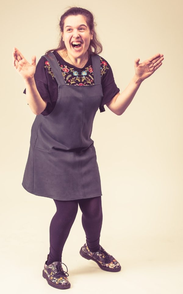 Rosie Jones laughing with her arms in the air in a photography studio